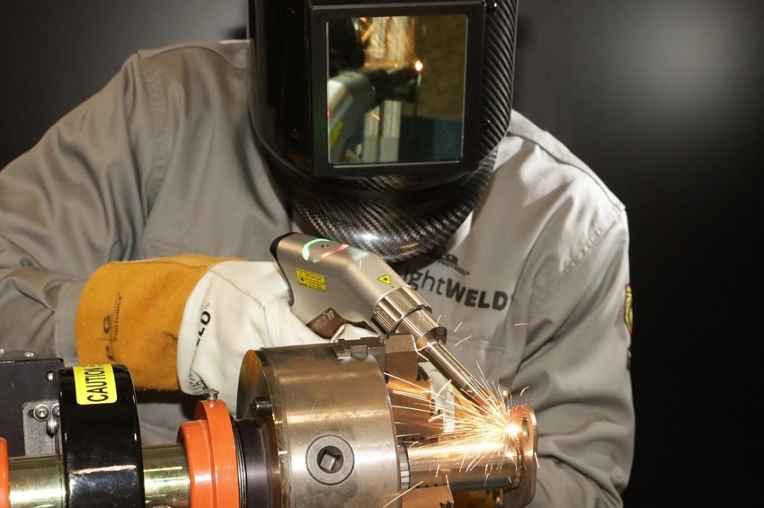 Soudeur en EPI réalisant une opération de soudage laser sur une pièce métallique